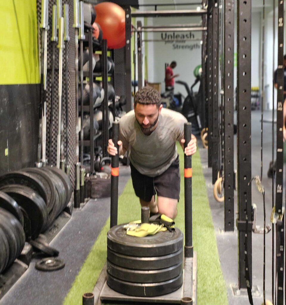 Man pushing sled at Function Health Club in Vancouver.
